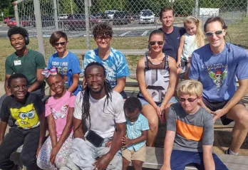 A group of dads and their kids take a break on the bleachers during family kickball.