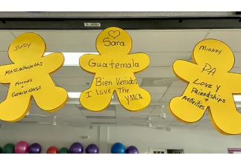 Three yellow human cut outs with black writing stuck on a mirror in exercise room at the Y
