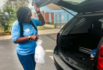 A YMCA volunteer loads a turkey into a trunk.