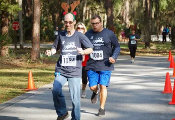 Runners outdoors at the 2023 Reindeer Run. Paved roads, orange cones and pine trees in the background