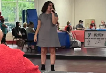 A MASH program participant performing karaoke indoors, in front of friends. The program, MASH, is for adults with physical, cognitive and developmental disabilities, including people who have autism.