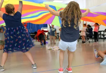 Kids lifting giant colorful round parachute during an indoor activity from BayCare Kids Power program.jpg
