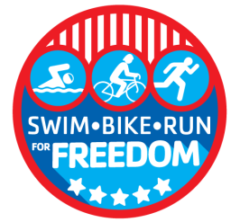 Logo for the Greater Palm Harbor Kids Triathlon 2022. Circle with red outline, bottom of circle is blue fill color and five white stars. Top of circle are white icons on light blue background,  red and white lines above. Text in white reads SWIM BIKE RUN for FREEDOM.