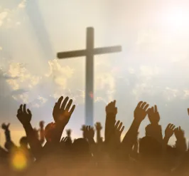 Religious cross with a sky backdrop and hands raised in prayer and worship.