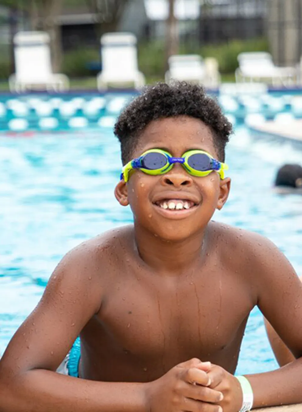 three boys smiling leaning on the pool edge