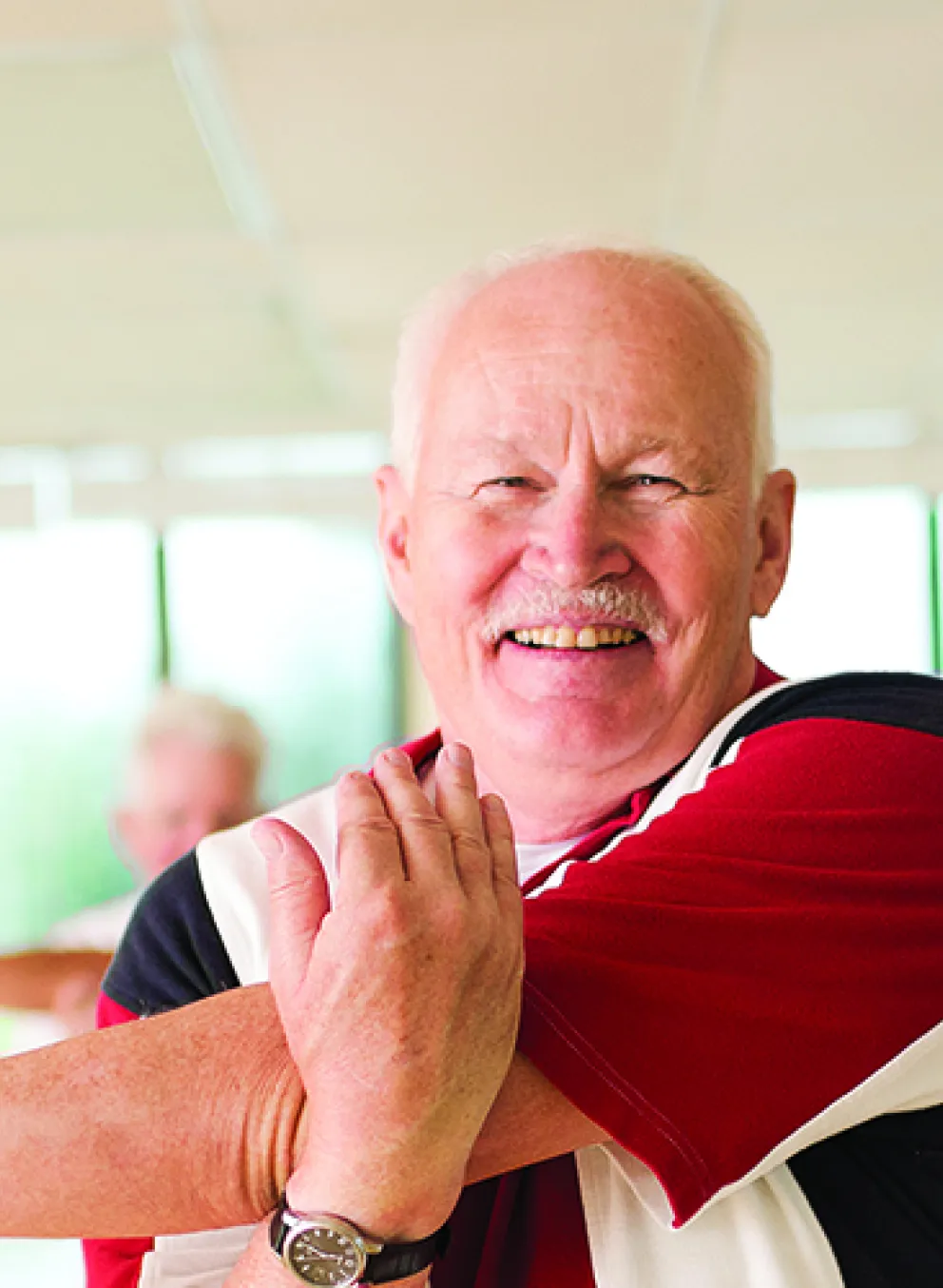 active older man doing light stretching in a group exercise class