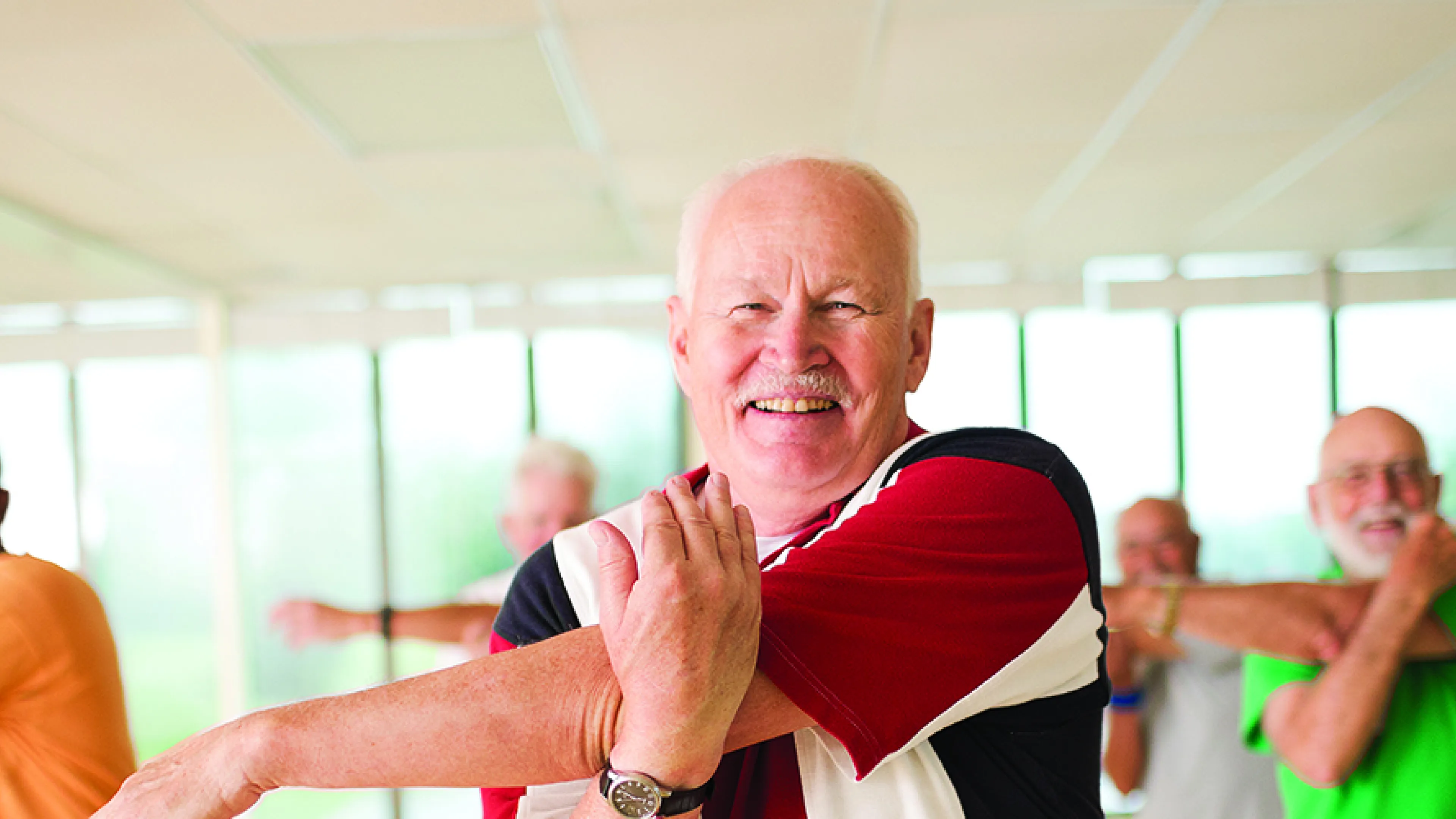 active older man doing light stretching in a group exercise class