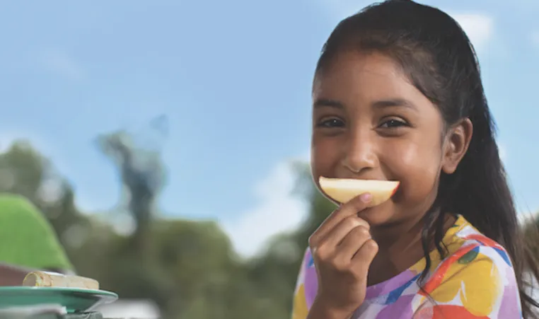 girl using apple slice as smile