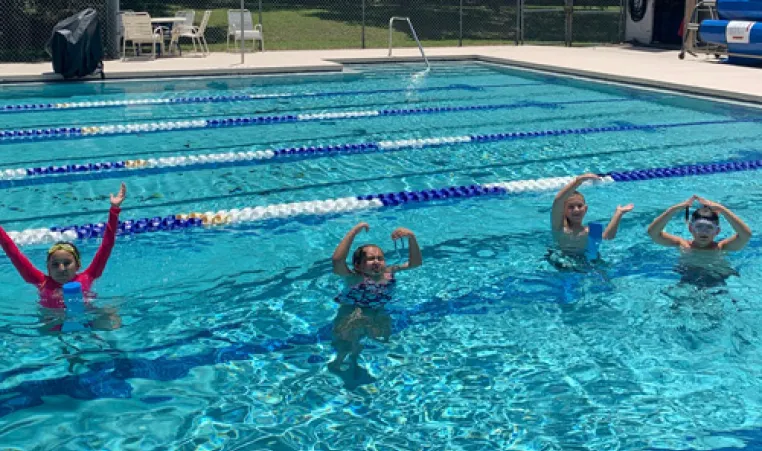 young swimmers in outdoor ymca pool making letters YMCA with arms