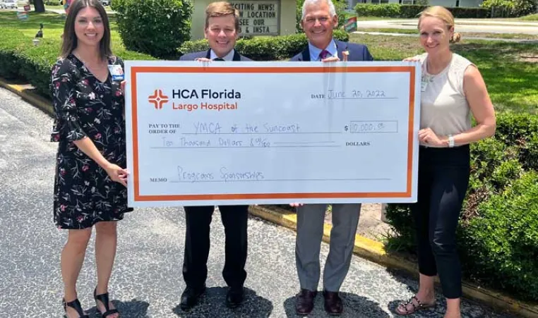 A check presentation from HCA Florida-Largo donation to the Greater Ridgecrest YMCA and Clearwater Y in Motion. Four people holding up the check.