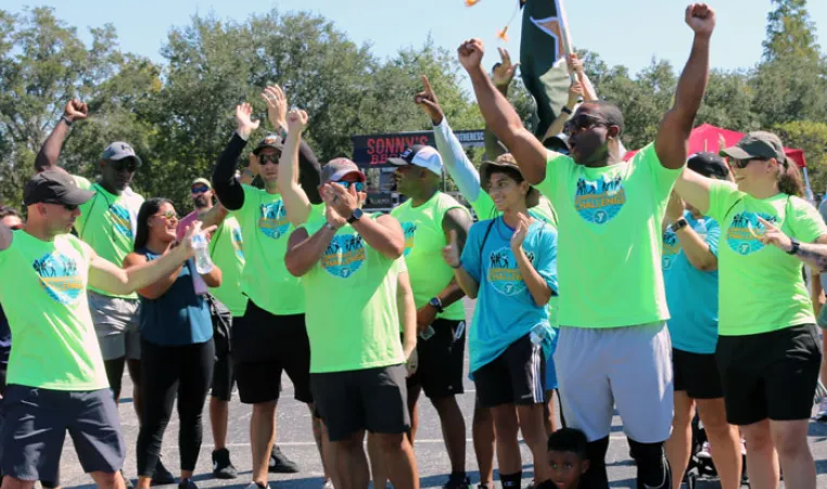 The winning team of the Corporate Cup Challenge, all wearing bright green shirts, cheer when they learned they won the 2022 games.