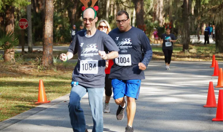 Runners outdoors at the 2023 Reindeer Run. Paved roads, orange cones and pine trees in the background