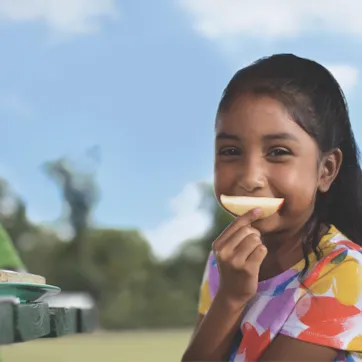girl using apple slice as smile
