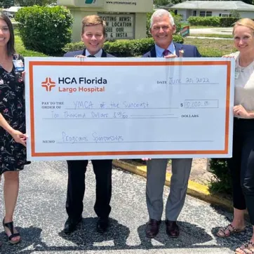 A check presentation from HCA Florida-Largo donation to the Greater Ridgecrest YMCA and Clearwater Y in Motion. Four people holding up the check. 