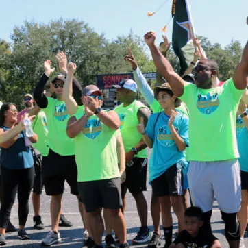The winning team of the Corporate Cup Challenge, all wearing bright green shirts, cheer when they learned they won the 2022 games.