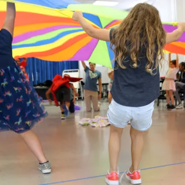 Kids lifting giant colorful round parachute during an indoor activity from BayCare Kids Power program.jpg