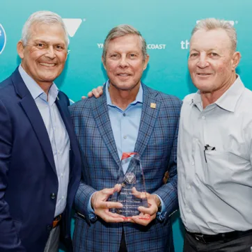 Three men on step and repeat at 2022 Annual Celebration. Man in the middle is holding a glass Order of the Red Triangle award.