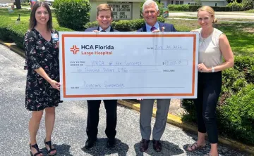 A check presentation from HCA Florida-Largo donation to the Greater Ridgecrest YMCA and Clearwater Y in Motion. Four people holding up the check. 
