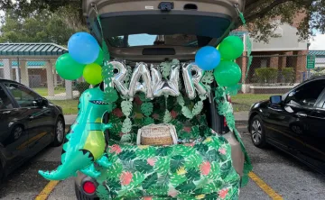 Open car trunk decorated in dinosaur in the jungle theme in a parking lot at a Trunk or Treat event.