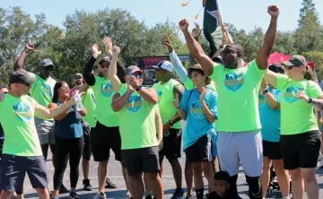 The winning team of the Corporate Cup Challenge, all wearing bright green shirts, cheer when they learned they won the 2022 games.