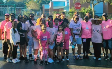 Group of people in a parking lot, wearing pink shirts at a cancer awareness event