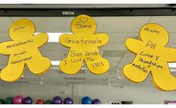 Three yellow human cut outs with black writing stuck on a mirror in exercise room at the Y