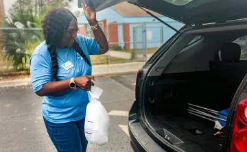 A YMCA volunteer loads a turkey into a trunk.