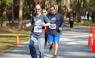 Runners outdoors at the 2023 Reindeer Run. Paved roads, orange cones and pine trees in the background