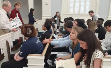 Teens in pews in a courtroom during a lecture. Foreground shows a student reading. The Youth in Government teen program attended the Florida State Assembly in February 2023. 