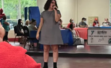 A MASH program participant performing karaoke indoors, in front of friends. The program, MASH, is for adults with physical, cognitive and developmental disabilities, including people who have autism.