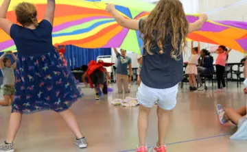 Kids lifting giant colorful round parachute during an indoor activity from BayCare Kids Power program.jpg
