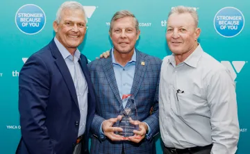 Three men on step and repeat at 2022 Annual Celebration. Man in the middle is holding a glass Order of the Red Triangle award.