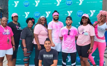 9 men and women standing in front of a YMCA logo backdrop