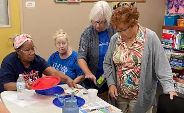 4 active older adult members (women) reading information
